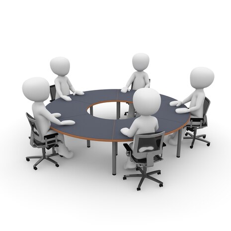 Grafik: Business-Meeting: Mehrere Personen sitzen an einem runden Tisch und besprechen sich.