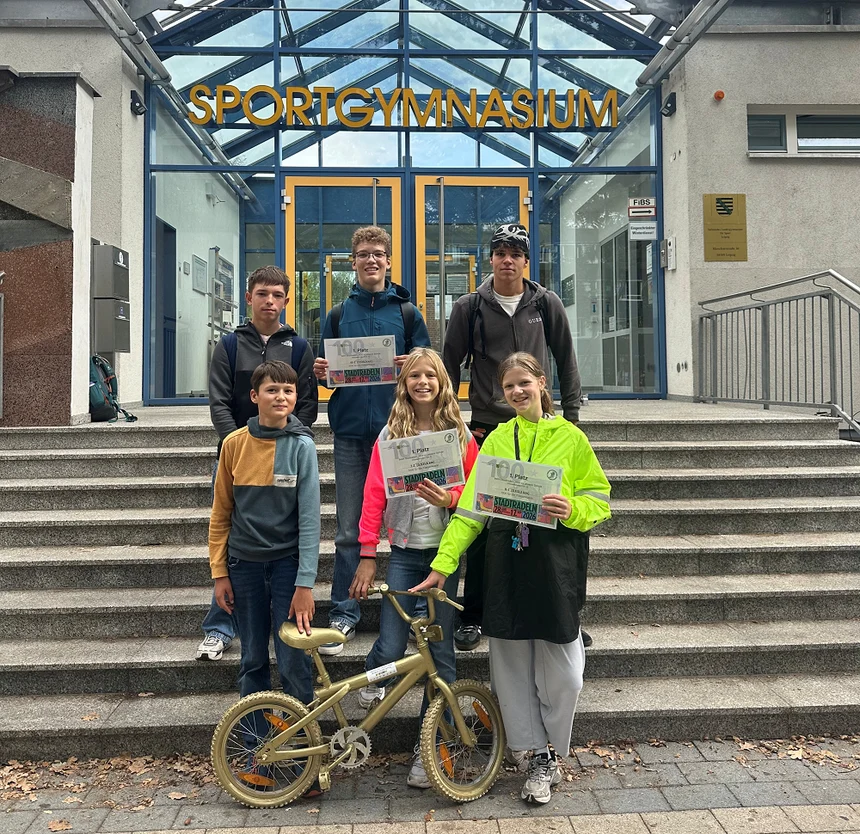 Foto: Ausgewählte Schülerinnen und Schüler mit dem Wanderpokal vor dem Schuleingang